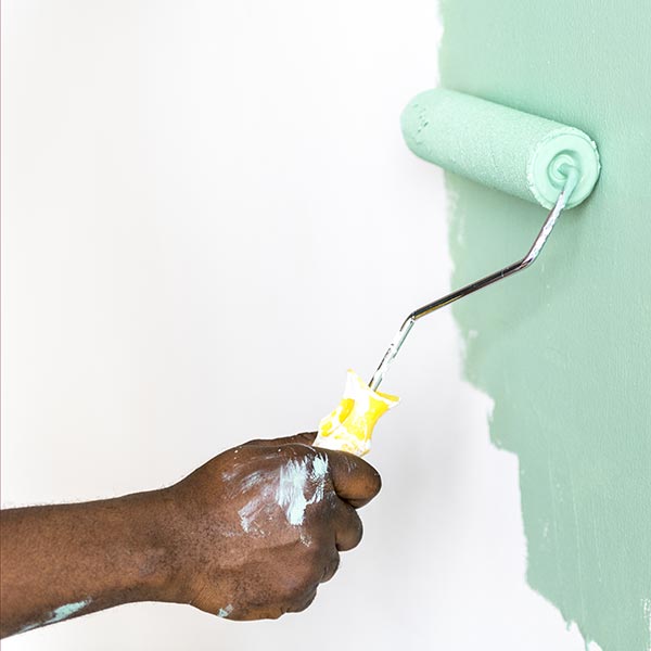 Man painting house wall with paint roller
